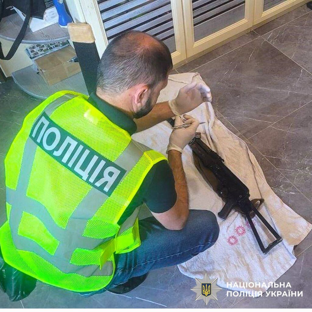 Поліцейський досліджує зброю на підлозі.