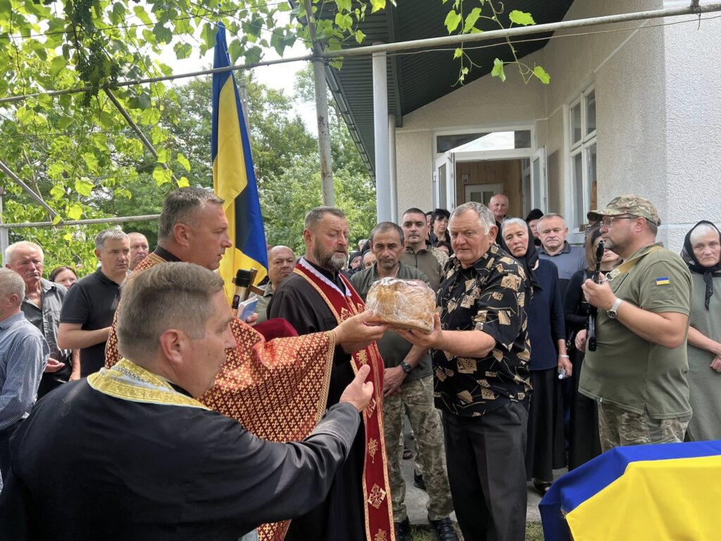 Церемонія вручення хліба на тлі українського прапора.