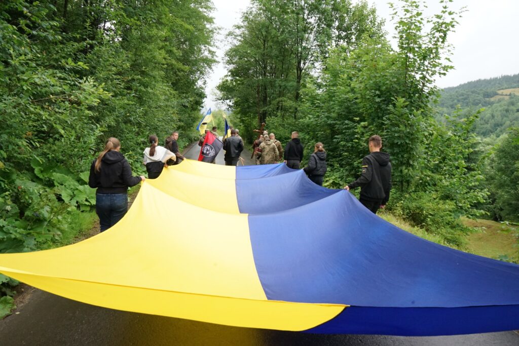 Люди несуть великий жовто-синій прапор дорогою