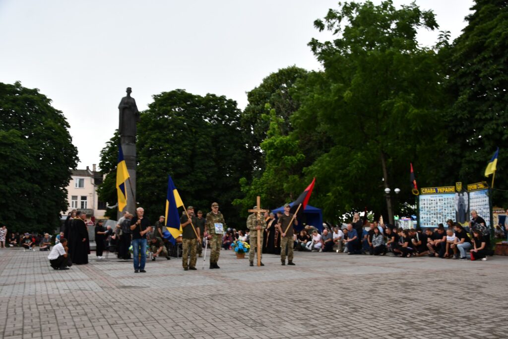 Люди з прапорами на площі біля пам'ятника.