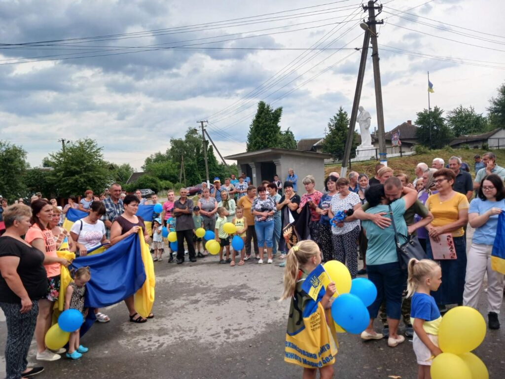 Група людей з українськими прапорами на вулиці.