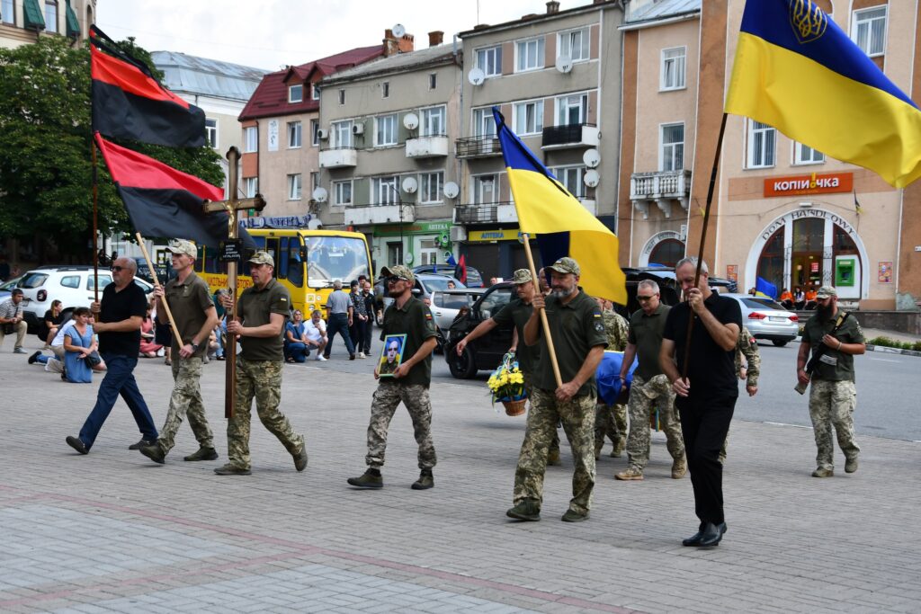Урочистий захід з українськими прапорами на вулиці.