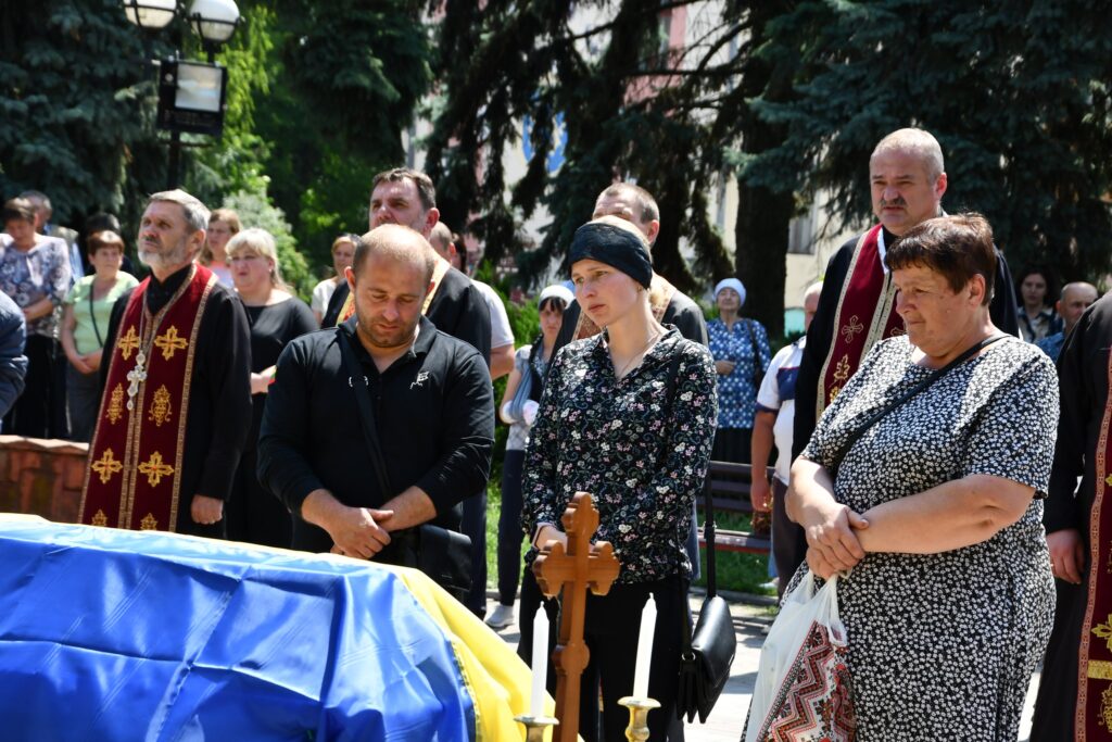 Люди на похороні біля труни з прапором.