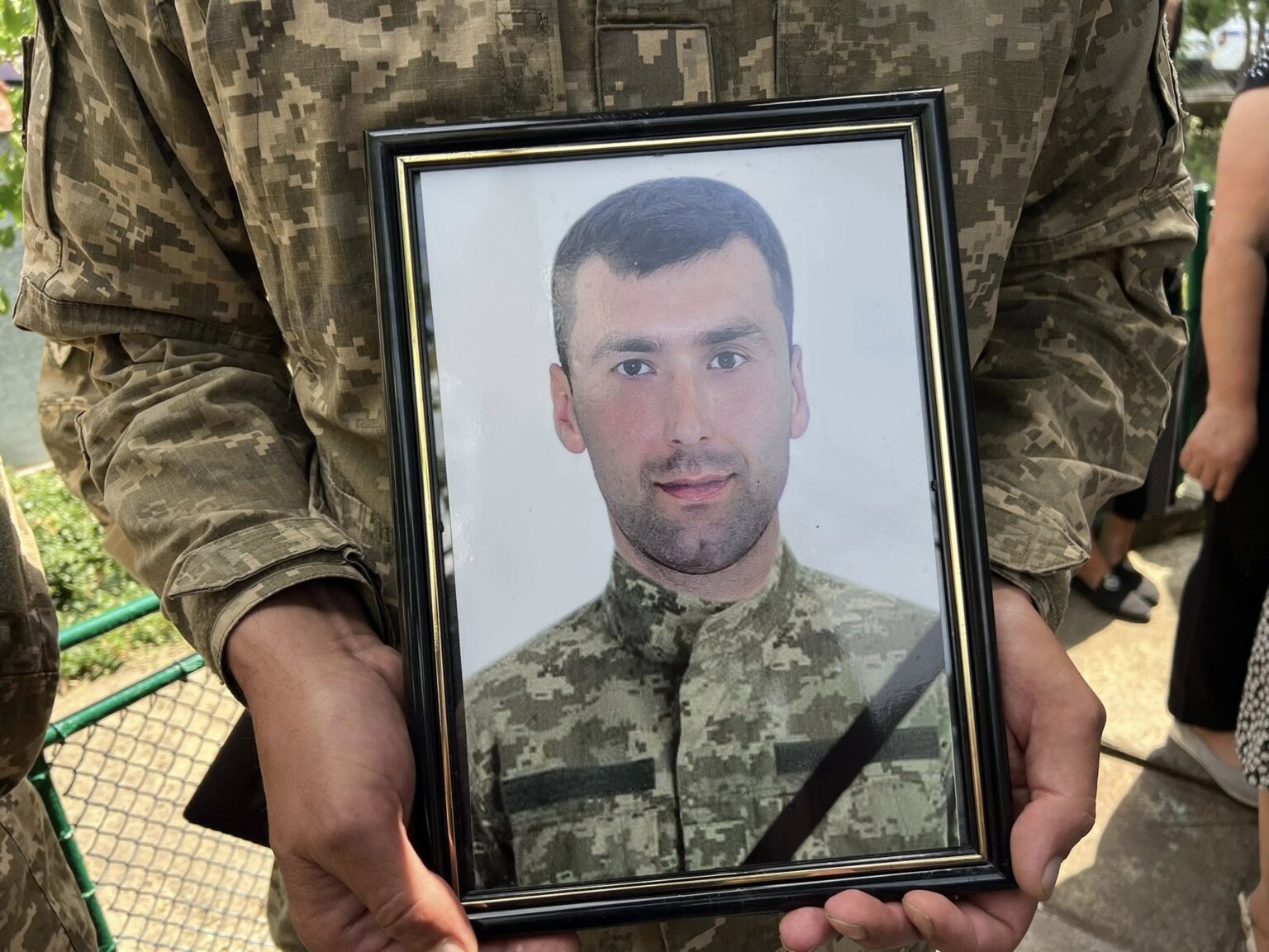 Фото військового в рамці, тримають у руках.