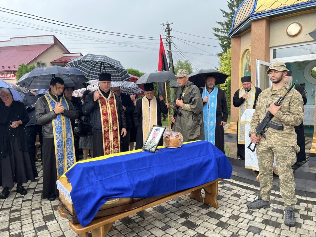 Церемонія прощання з військовим у дощову погоду.