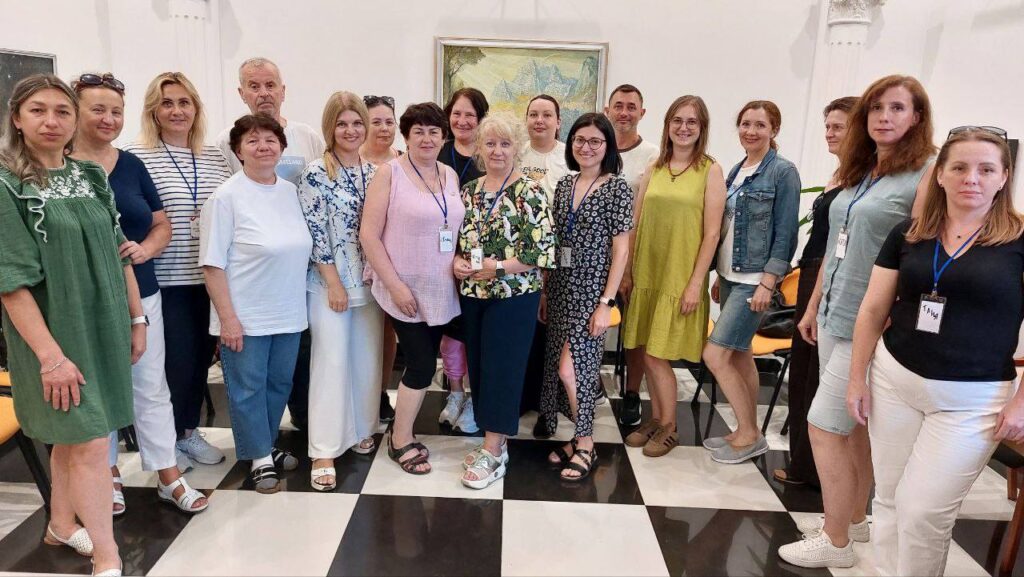 Групове фото людей у приміщенні з малюнком.