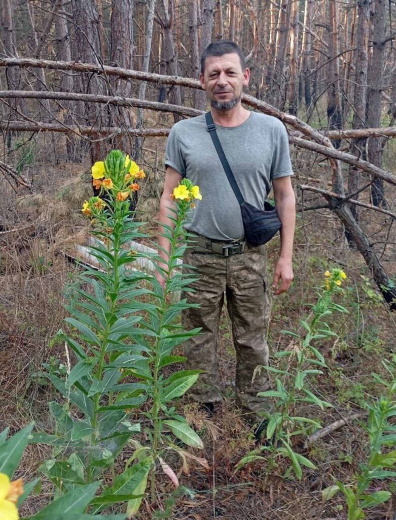 Чоловік у лісі з квітами жовтими.