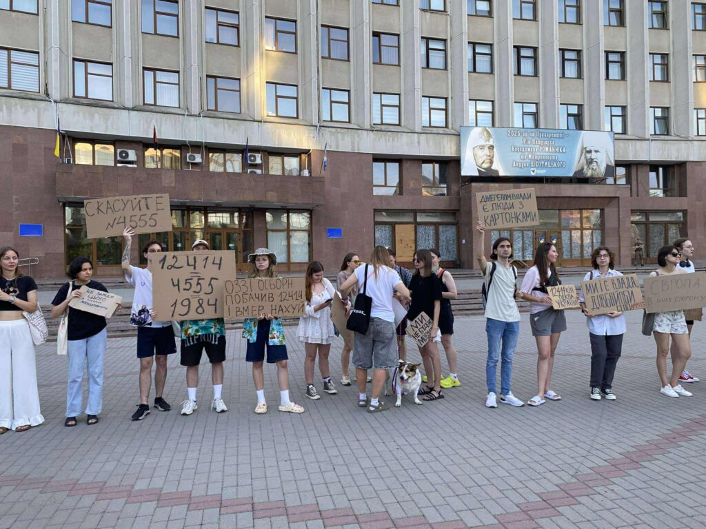 Протестувальники тримають плакати перед будівлею в місті.