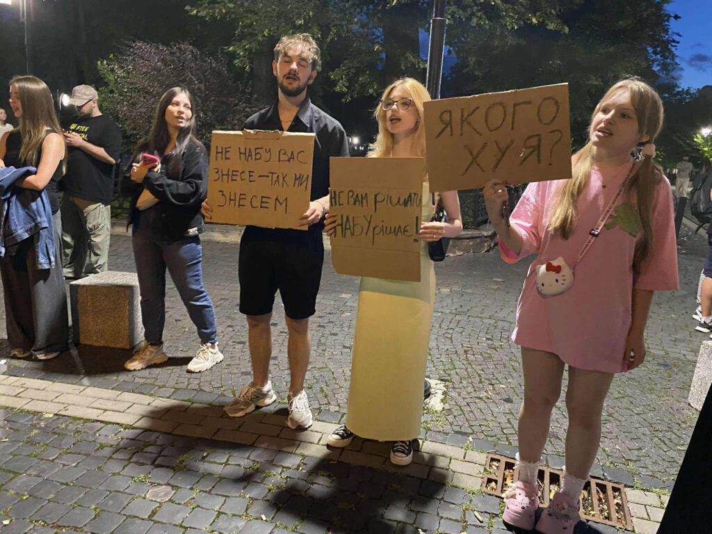 Люди на вулиці тримають плакати з гаслами.