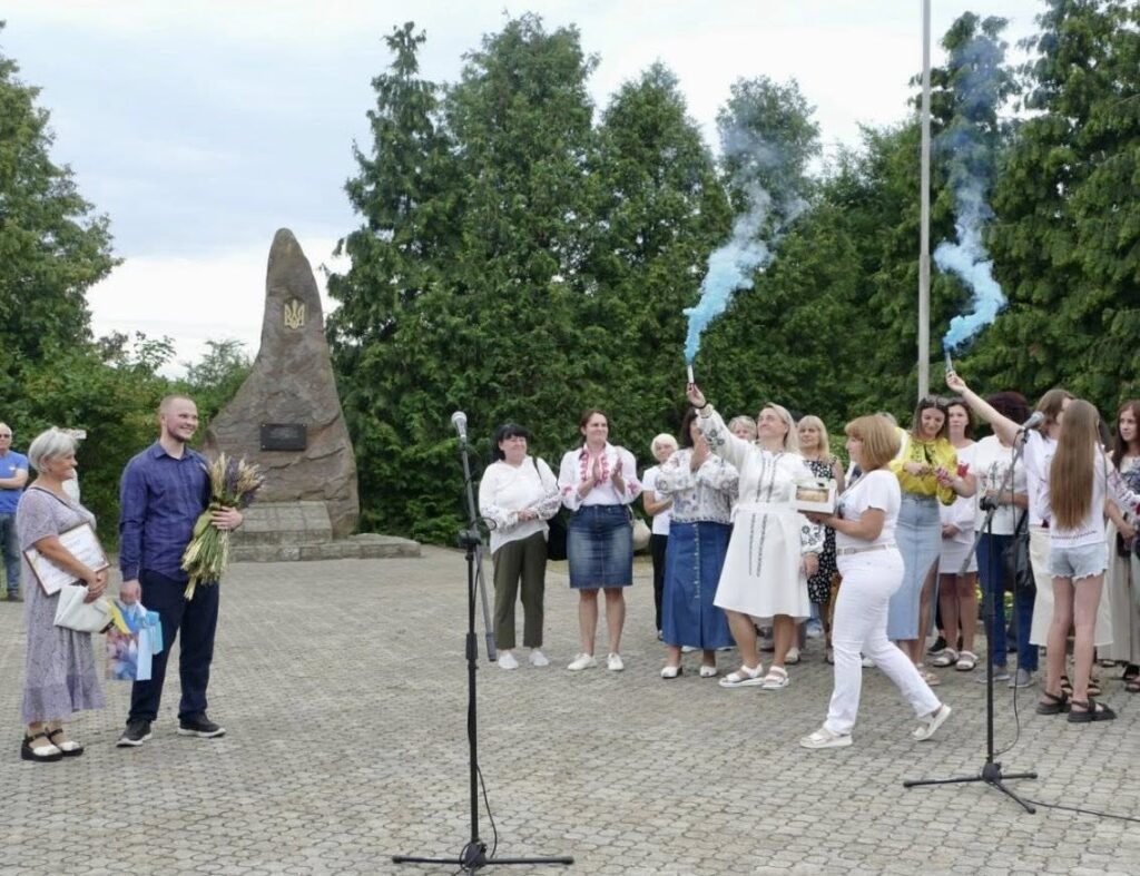 Група людей святкує біля пам'ятника.