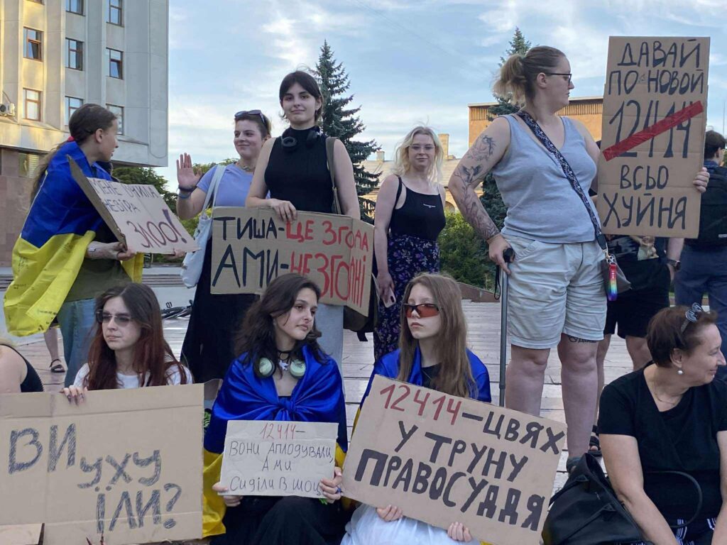 Протест на площі з плакатами та прапорами.
