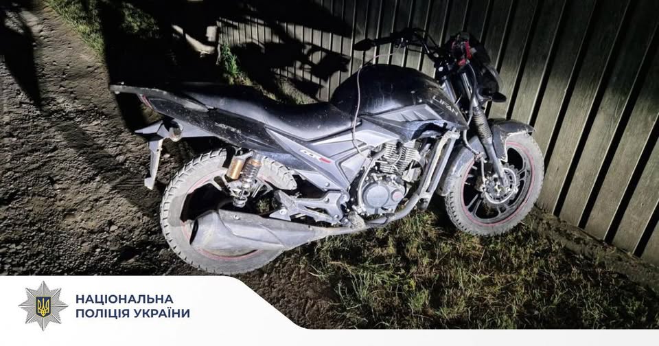 Чорний мотоцикл біля паркану вночі