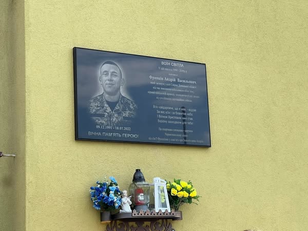 Меморіальна дошка герою України з квітами.