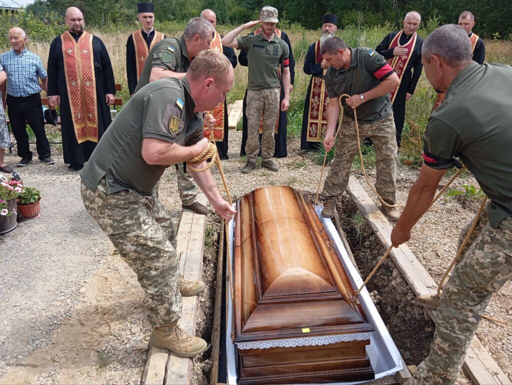 Військові опускають труну на похороні.