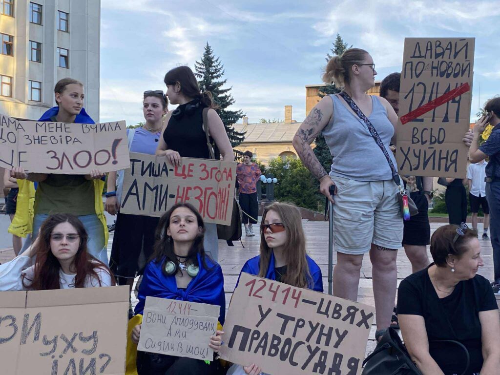 Люди на протесті з плакатами в Україні.