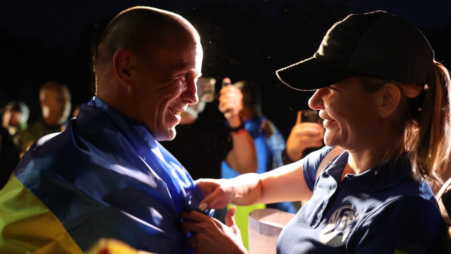 Люди радісно обгорнуті в український прапор вдень.