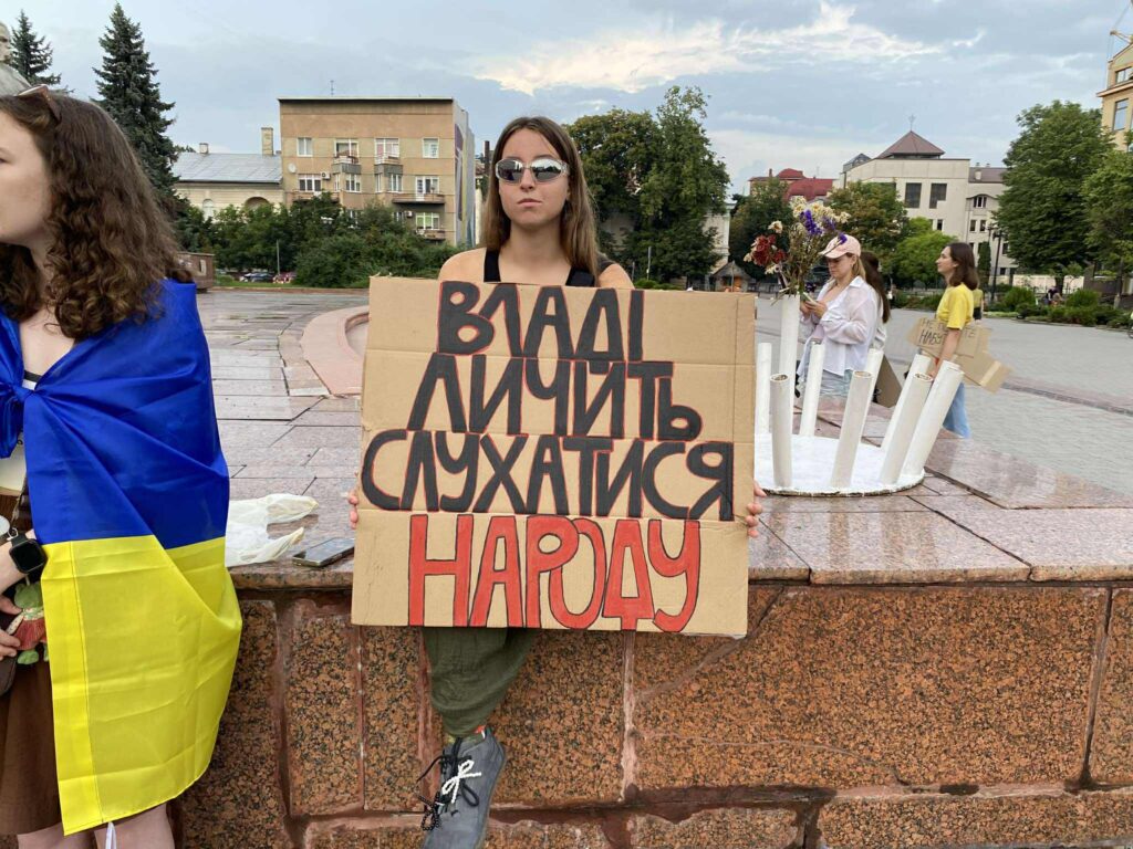 Жінка тримає плакат на протесті в Україні.