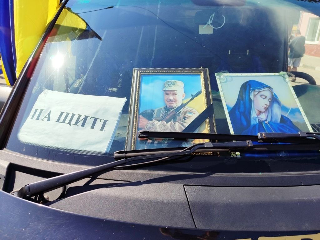 Лобове скло авто з портретами та прапорами.