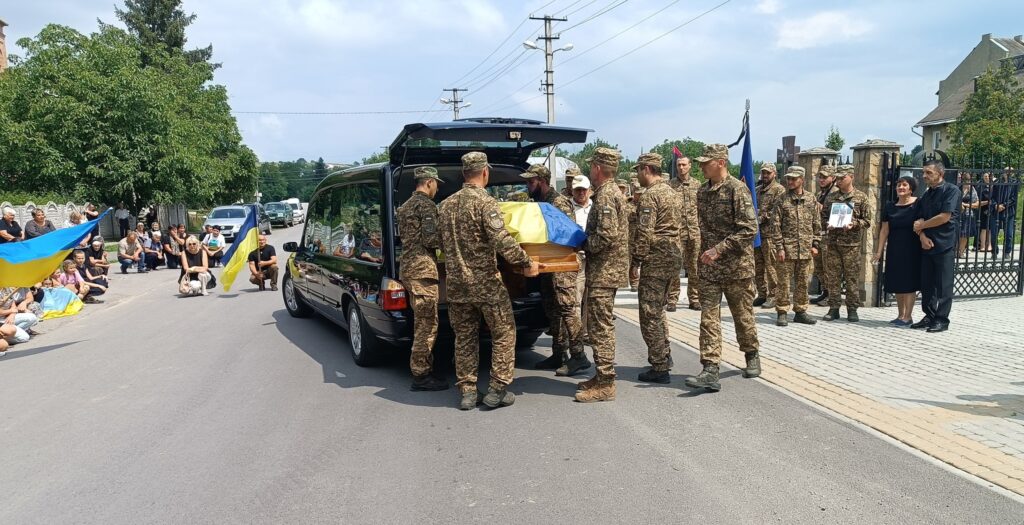 Військові несуть труну під українським прапором.