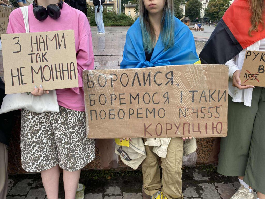 Протест проти корупції з плакатами і прапорами.