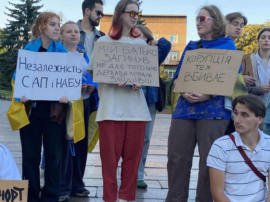 Люди на демонстрації з плакатами проти корупції.