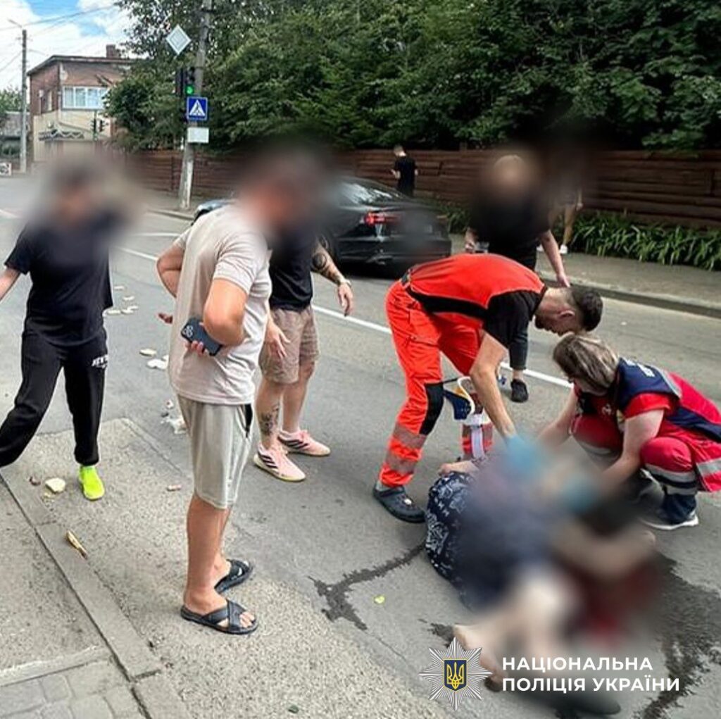 Люди допомагають постраждалому на вулиці, поліція України.