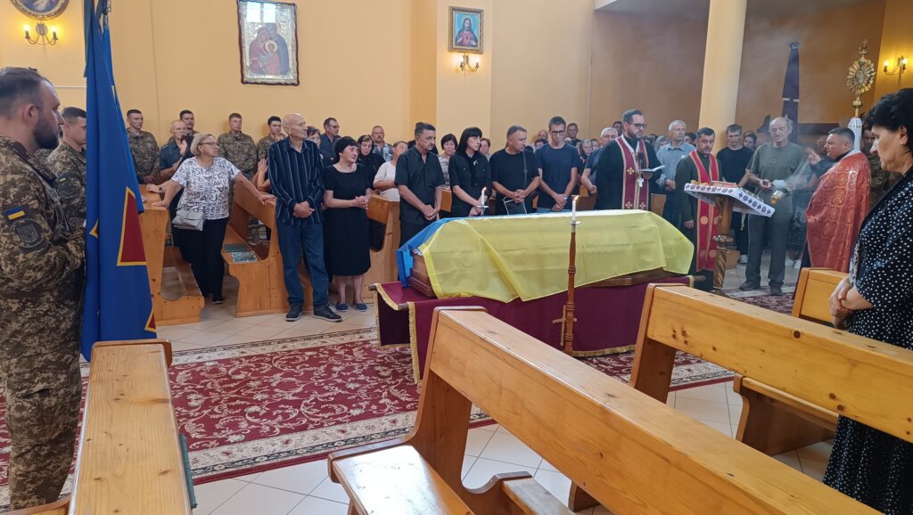 Похоронна служба із жовто-блакитним прапором в церкві.