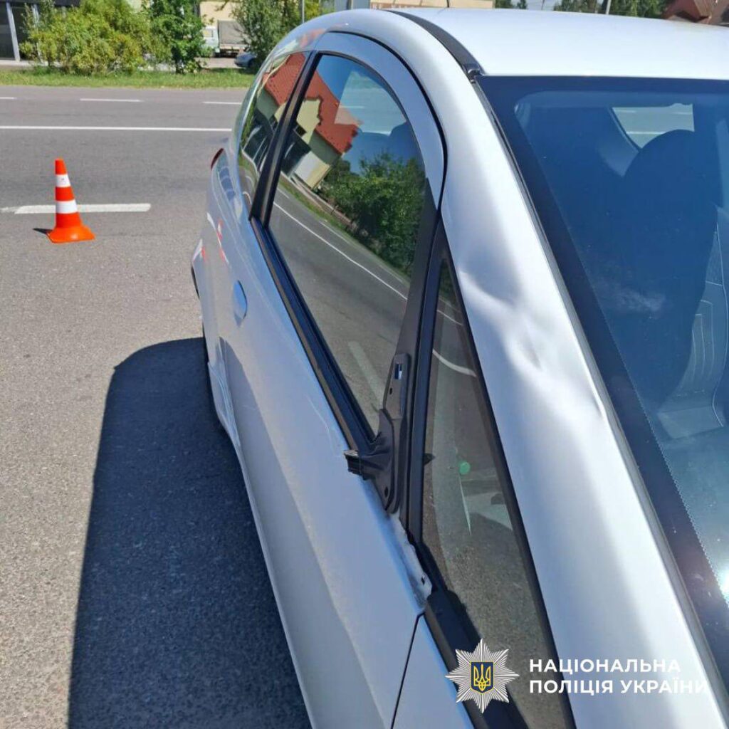 Пошкоджене авто біля дорожнього конуса на дорозі.