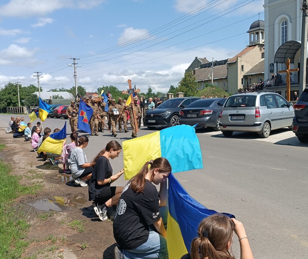 Люди з прапорами на вулиці в Україні.