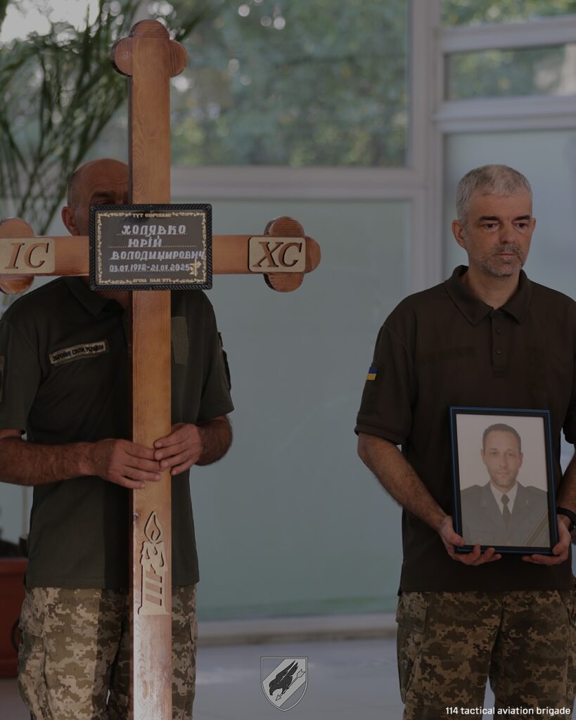 Військові тримають хрест і портрет померлого офіцера.