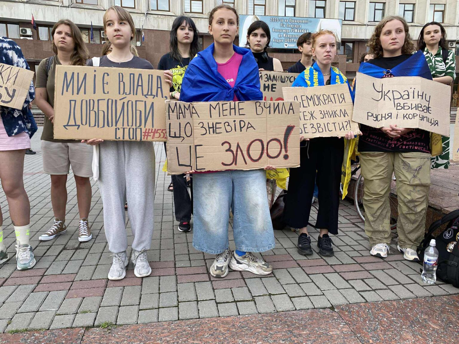 Протестувальники тримають плакати з різними гаслами.