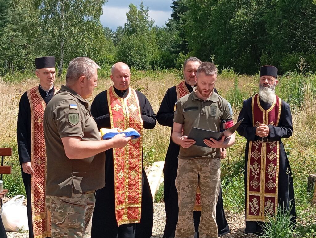 Церемонія на відкритому повітрі з військовими та священиками.