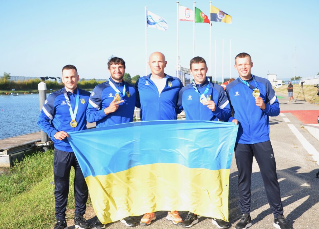 Спортсмени з медалями і українським прапором на фоне