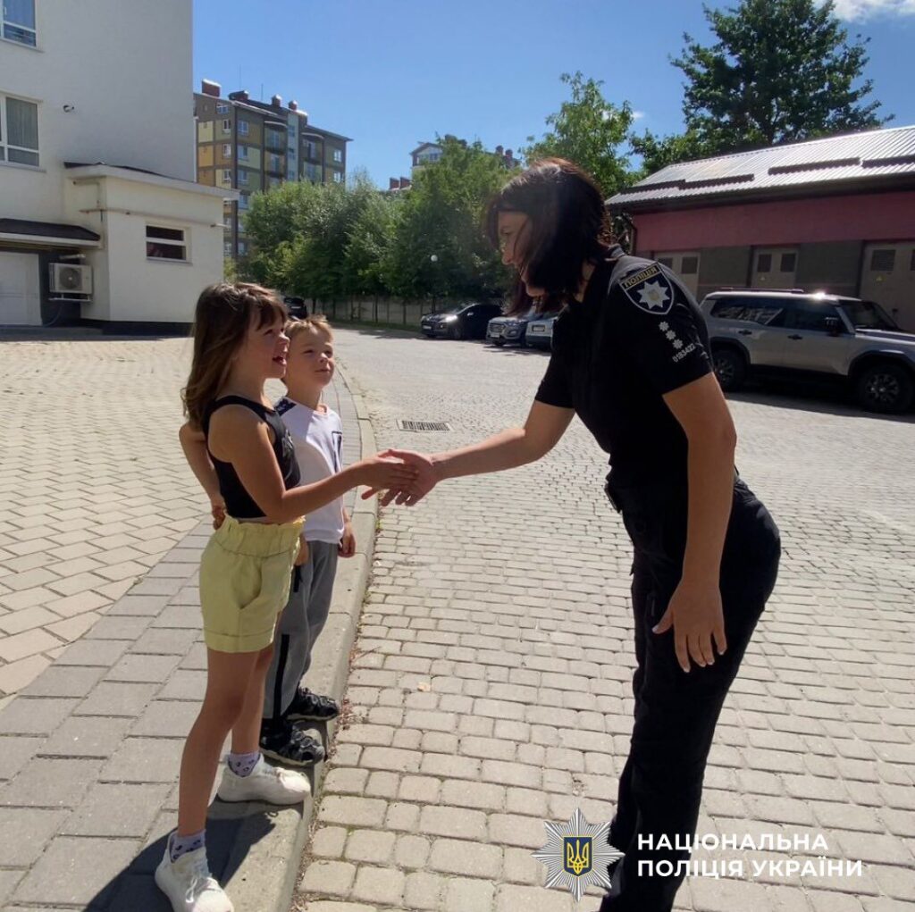 Поліцейська вітається з дітьми на вулиці.