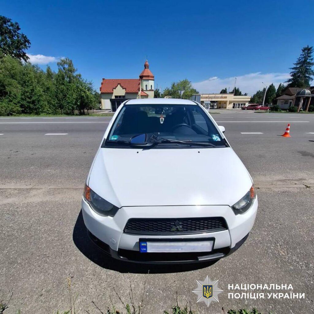 Білий автомобіль на дорозі біля церкви.