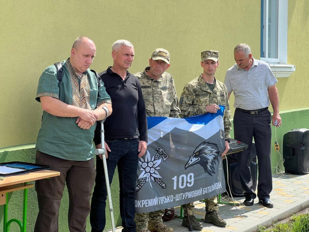 Група людей тримає прапор батальйону на вулиці.