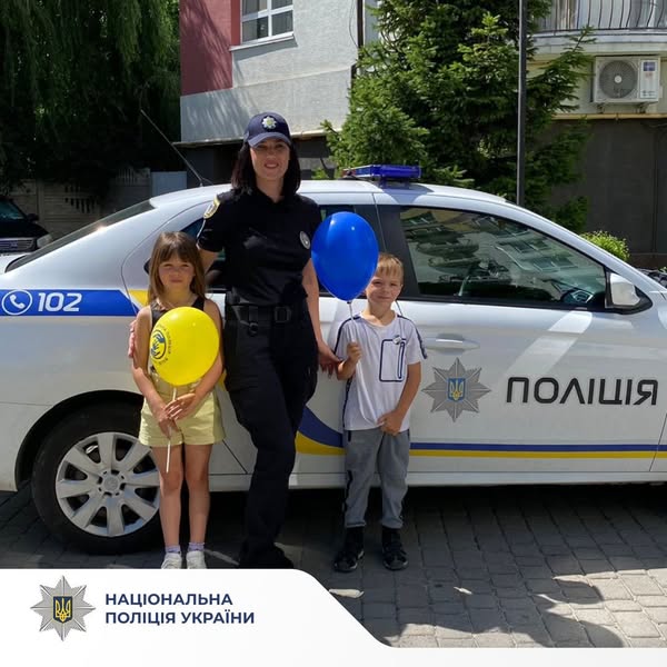 Поліцейська з дітьми біля поліцейської машини