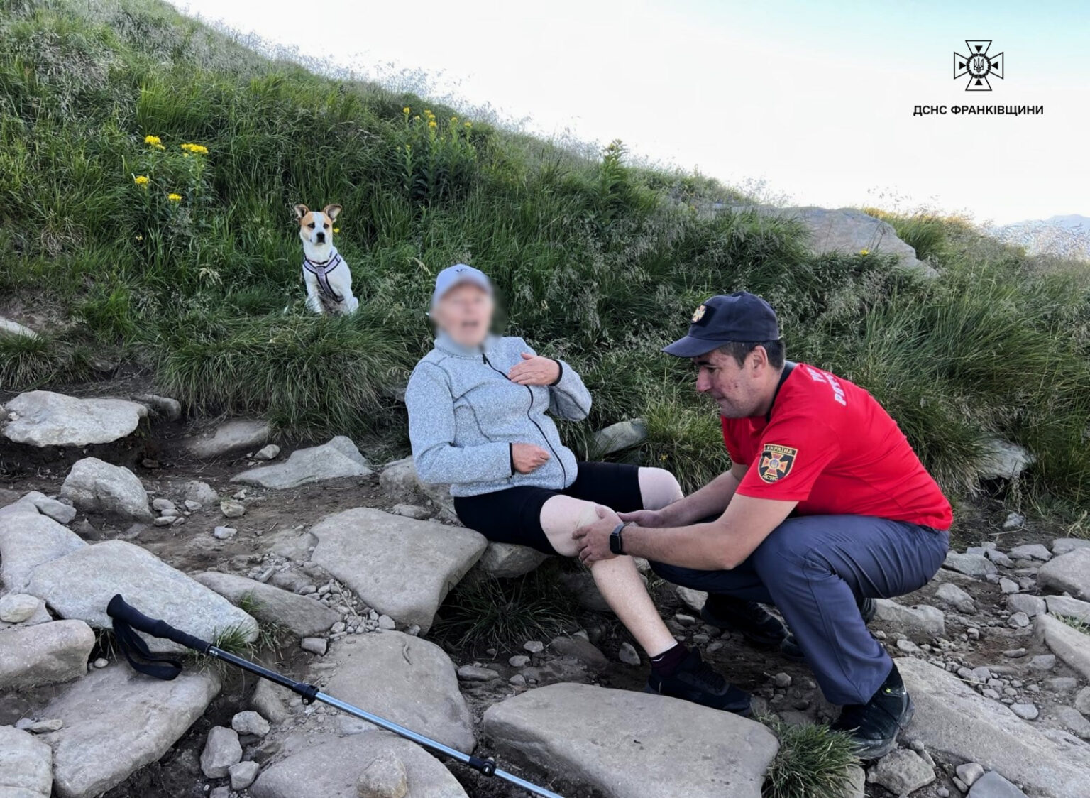 Рятувальник допомагає туристу на кам'янистій стежині.