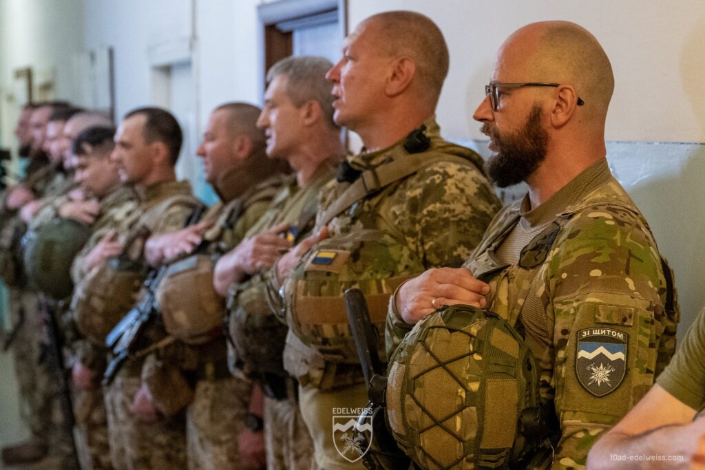 Українські військові в строю з прапором на формі.