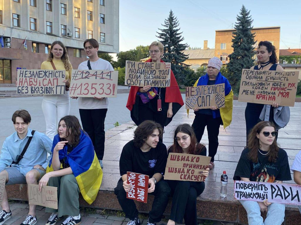 Люди з плакатами на демонстрації в Україні.