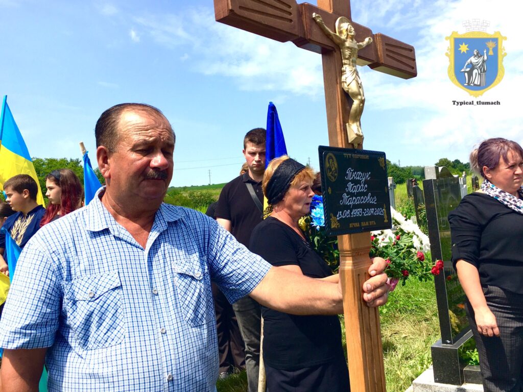 Люди на цвинтарі з прапорами України