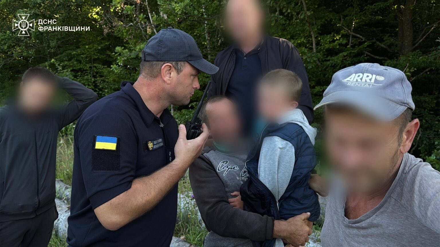 Рятувальник допомагає групі людей у лісі.