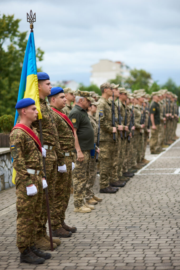 Українські військові в строю з флагом.