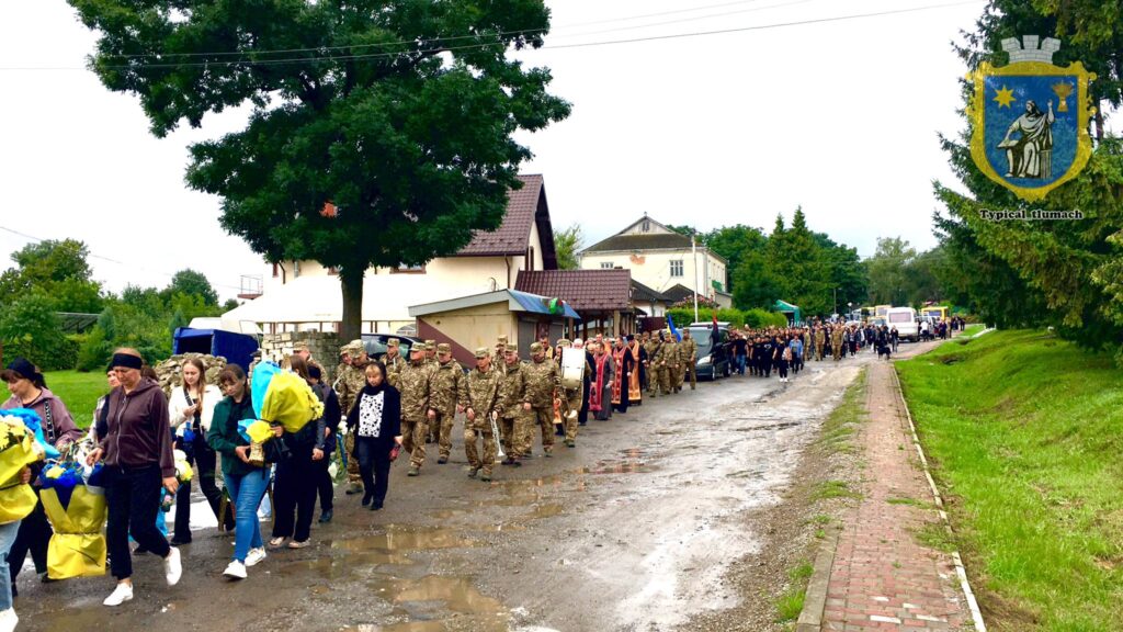 Процесія людей з квітами та військовими
