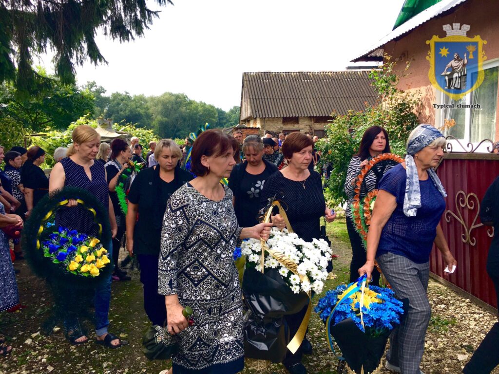 Група людей несе квіти на церемонію вшанування.