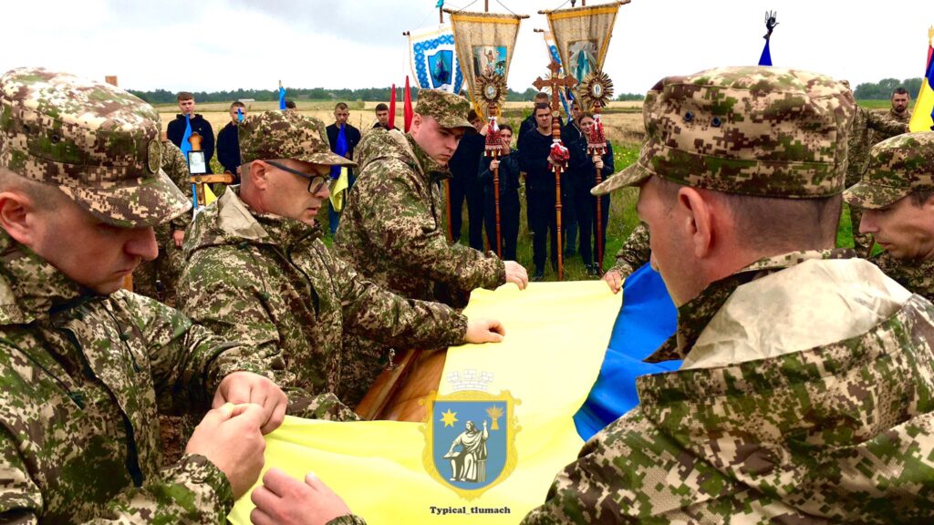 Військові розгортають український прапор на вулиці.