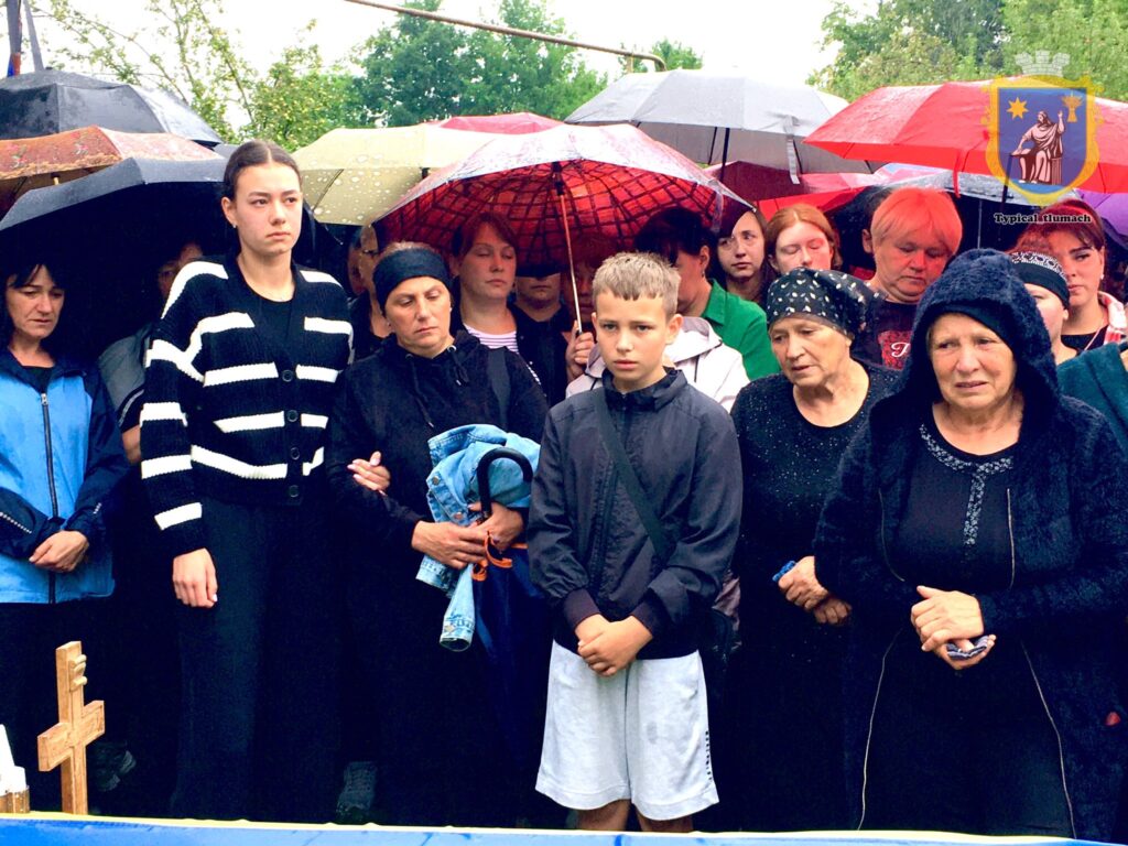 Люди стоять під парасолями на вулиці