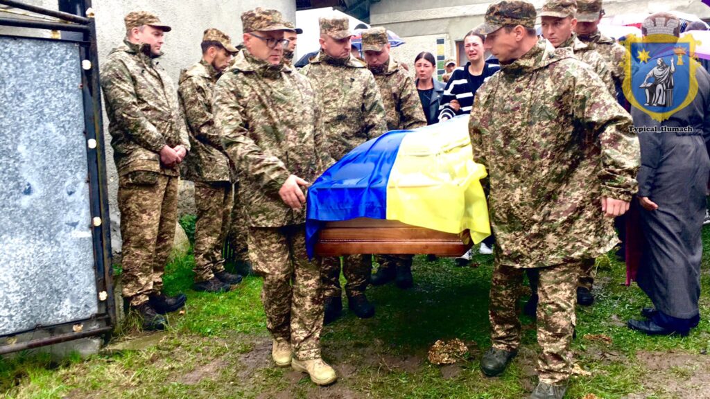 Військові несуть труну під прапором України.