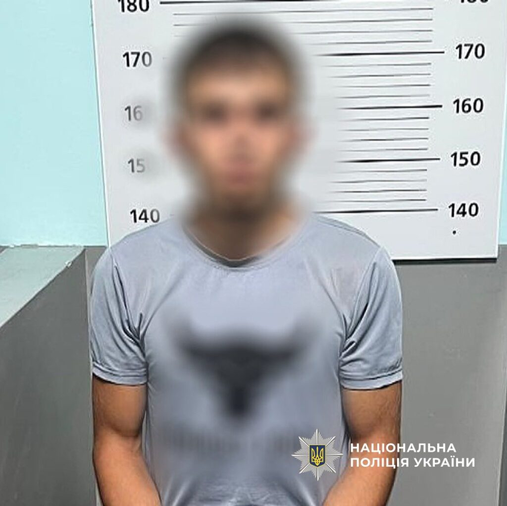 Затримана особа перед вимірником зросту у відділку.