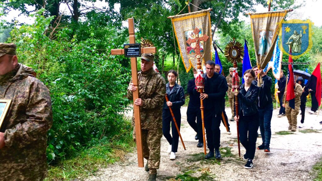Люди несуть хрести і прапори в процесії.